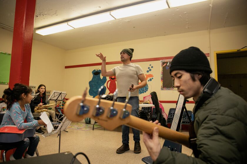 Daniel Chávez, executive director of People’s Center for Cultural and Contemporary Arts, speaks to students during rehearsal at the Dvorak Fieldhouse in the Pilsen. Meanwhile, musician and instructor Take Yokoyama, 23, plays the bass.