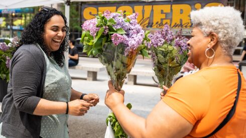 Lillian Wilkins (right) and Rohini Bapu (left), who are on their lunch break, look at flowers on the first day of the Daley Plaza City Market at Daley Plaza in the Loop, Thursday, May 11.