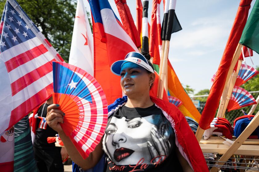 A vendor holds a hand fan with the Puerto Rican flag printed on it during the Puerto Rican People’s Day Parade Saturday.