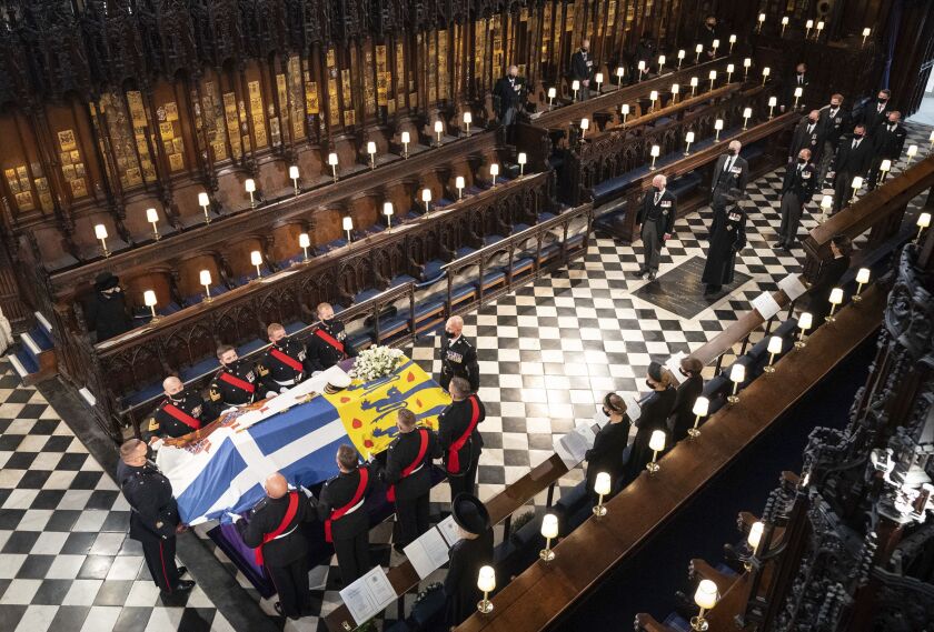 Queen Elizabeth watches as pallbearers carry the coffin of the Duke of Edinburgh during his funeral, at St George’s Chapel in Windsor Castle, Windsor, England, Saturday April 17, 2021.