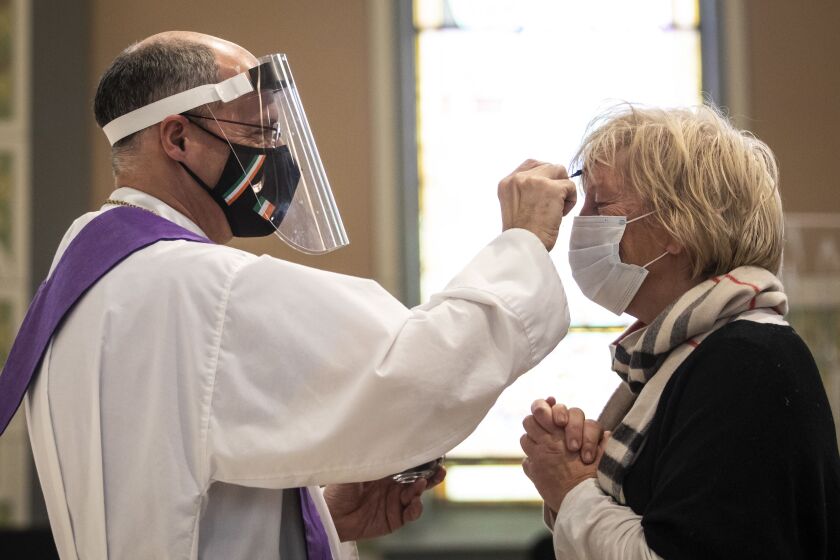 Lori Hiltz, 60, of Streeterville, receives the imposition of ashes from Rev. Tom Hurley at Old St. Patrick’s Catholic Church on the Near West Side on Ash Wednesday. Amid fears of the coronavirus pandemic, Hurley did not touch anyone and gave out ashes on a fresh Q-tip to each parishioner, then threw the Q-tip away.
