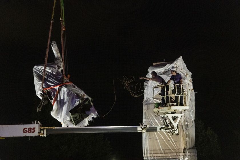 A crane lowers the Christopher Columbus Statue to the ground in Grant Park, Friday, July 24, 2020.