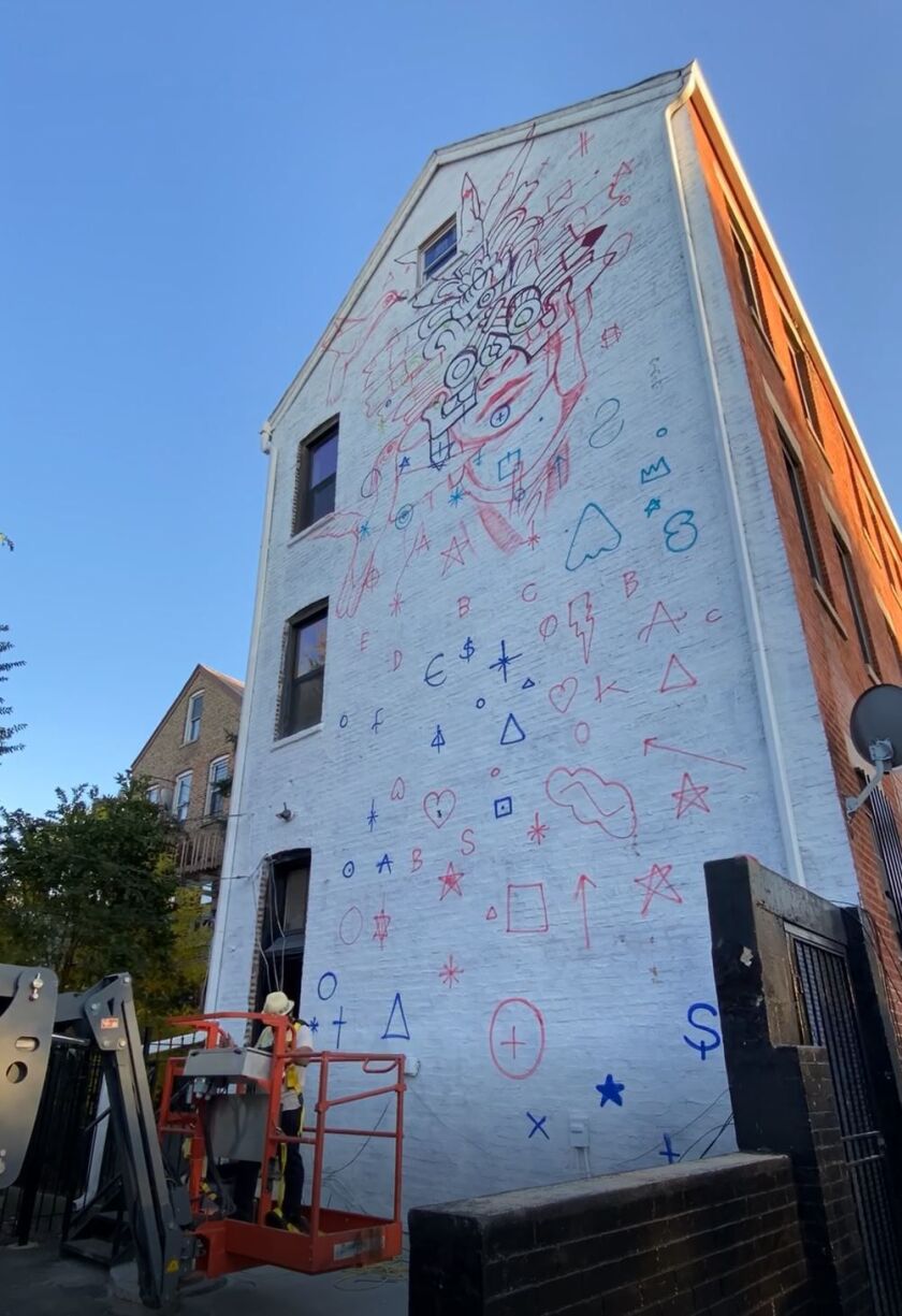 The artist SENKOE used a cherry picker to get up high enough to paint a mural in 2020 next to a Pilsen park.