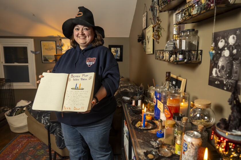 The “Bears Witch” Amanda Marron stands next to her altar while holding her grimoire in her home office in Wheaton.