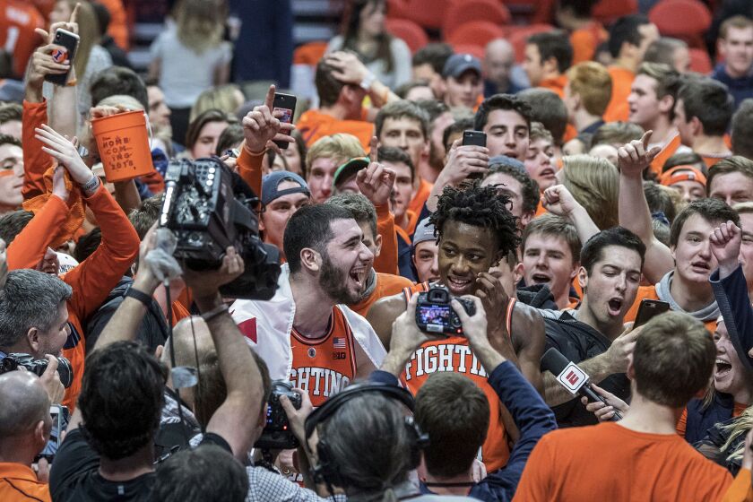 Illinois forward Giorgi Bezhanishvili, left, and guard Ayo Dosunmu (11) are swarmed by fans after the team’s NCAA college basketball game against Michigan State in Champaign, Ill.