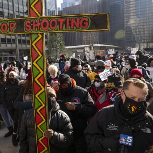 A protestor holds up a large wooden cross during a protest against the violence in the city of Chicago on N. Michigan Ave in Magnificent Mile, Thursday, Dec. 31, 2020.