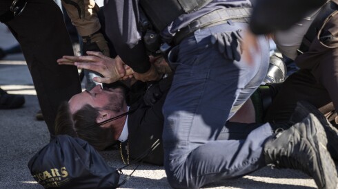 Rev. Michael Woolf is detained during a protest on Beach Street near the U.S. Immigration and Customs Enforcement facility in Broadview, Friday, Nov. 14, 2025.