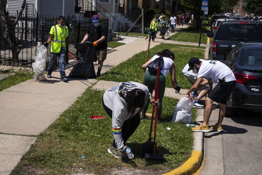 Volunteers pick up litter and clean up near West 23rd Street and South Cicero Avenue on Tuesday in Cicero after looting and violence spread through the town.