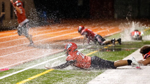 Lake View football players dive into puddles after winning the game against Von Steuben at Lane Stadium.