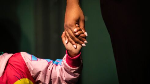 Lizzette, 6, holds hands with counselor Kierra Towns, 25, during Hearts to Art, a summer camp for children with parents who have died.
