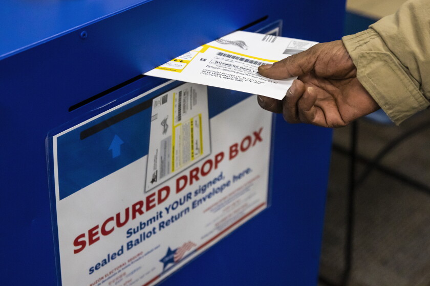 An early voter drops a municipal election mail-in ballot in the secured drop box at the Lincoln Park branch library in 2023.