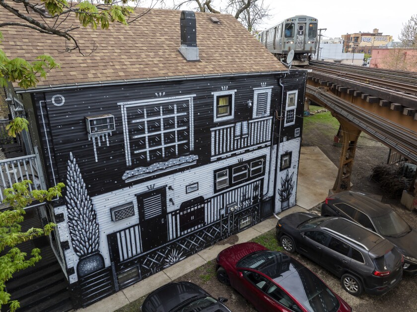 A Forest Park-bound Blue Line train passes by a Logan Square building painted by muralist Nick Fisher.