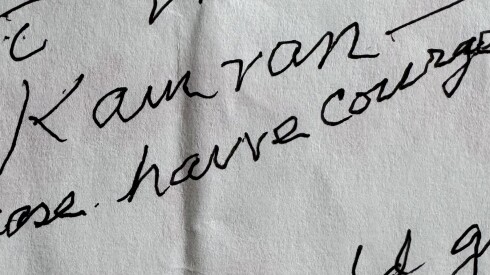 A piece of paper reads "For Kamran — "please have courage." The word "glasses" can be seen on the bottom right of the paper.