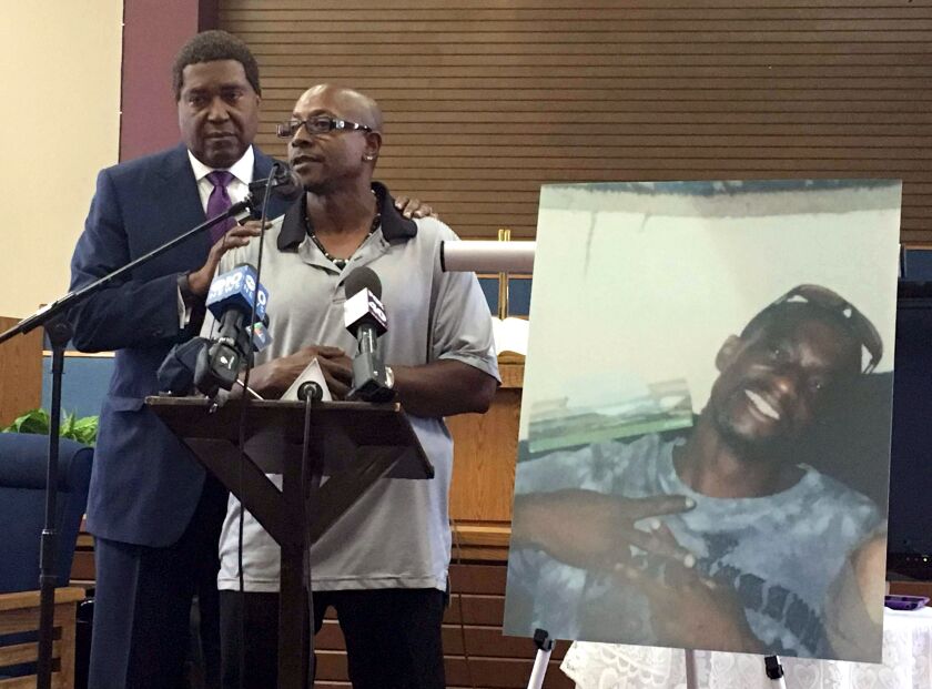 Robert Mann Sr. (right), addresses community members and reporters at Allen Chapel AME Church in Sacramento, California, accompanied by attorney John Burris on Aug. 5, 2016. Displayed at right is a photo of Mann’s brother, Joseph Mann, who was shot 14 ti
