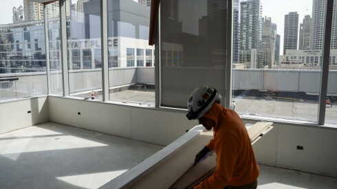 A worker, kneeling down, handles wood inside an under-construction two-bedroom unit at 111 W. Illinois St. in River North.