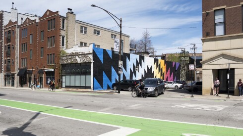 A colorful mural appears on the side of a building adjacent to a parking lot on North Milwaukee Avenue.