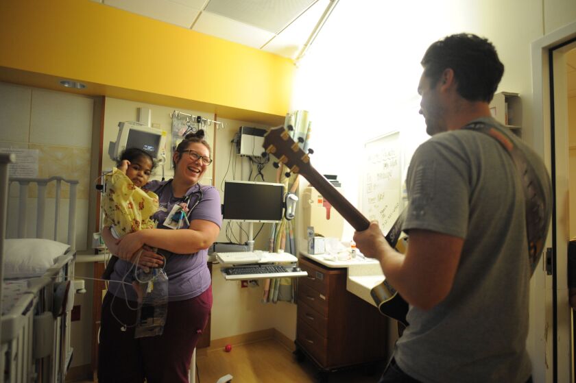 Nurse Ashley Kinner holds 19-month-old Malachi Gardner as they listen to Phil Fensel performance, volunteer musician from Musicians On Call, visiting Ann & Robert H. Lurie Children’s Hospital of Chicago
