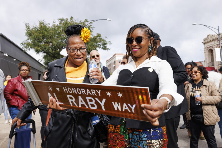 Katanya Raby, granddaughter of Al Raby, holds a sign dedicated for her grandfather at the corner of South Cottage Grove Avenue and East 64h Street during a street sign unveiling for Al Raby in Woodlawn, Friday, Oct. 16, 2026. Al Raby was a Chicago civil rights leader, educator, and political strategist.