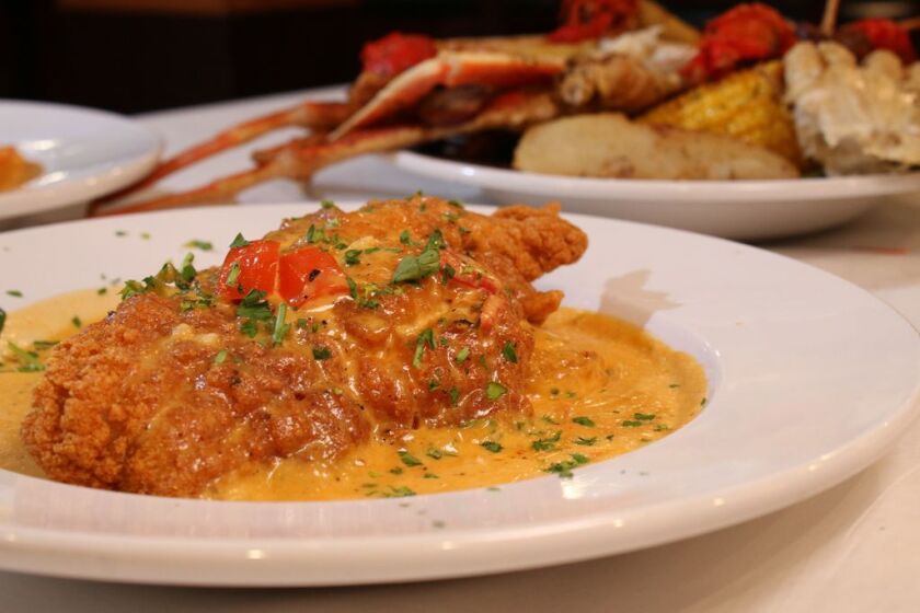 The catfish and grits, made at Hidden Manna Cafe, is fried catfish served over a bed of spicy cajun fried grit cakes covered in a garlic, onion, red and green pepper, and cream sauce.