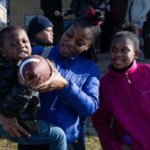 (From left) Gregory Martin, Breana Bolling and Aniyah Grant receive gifts as tow trucks deliver toys in Englewood during an early Christmas Eve event to surprise the children of two mothers killed while working as peacemakers in Chicago.