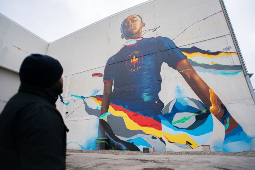 This mural, commissioned by the Chicago Fire, was painted this year by artist Max Sansing, who’s shown at left.