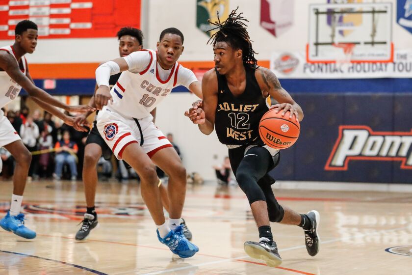 Joliet West’s Jamere Hill (12) moves the ball past Curie’s Josiah Hammons (10).