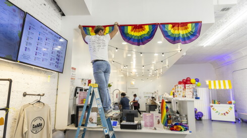 Jesse Diaz, owner of Hegewisch Nutrition, an LGBTQ+ friendly business in an old theater in downtown Hegewisch decorates for Pride month.