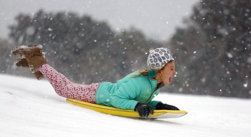 Finley Bork, 7, uses a boogie board, typically used on the beach, for sledding down a hill on a golf course at the Isle of Palms, S.C., on Wednesday. A brutal winter storm smacked the coastal Southeast with a rare blast of snow and ice Wednesday, hitting