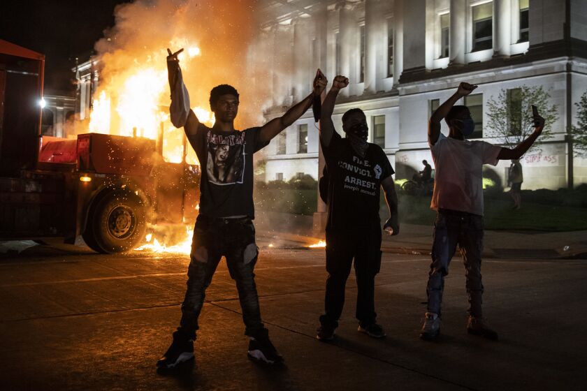 Protesters pose in front of a burning truck outside the Kenosha County Courthouse, where police clashed with protesters in the second night of unrest after police shot Jacob Blake in the Wisconsin city, Monday night, Aug. 24, 2020.