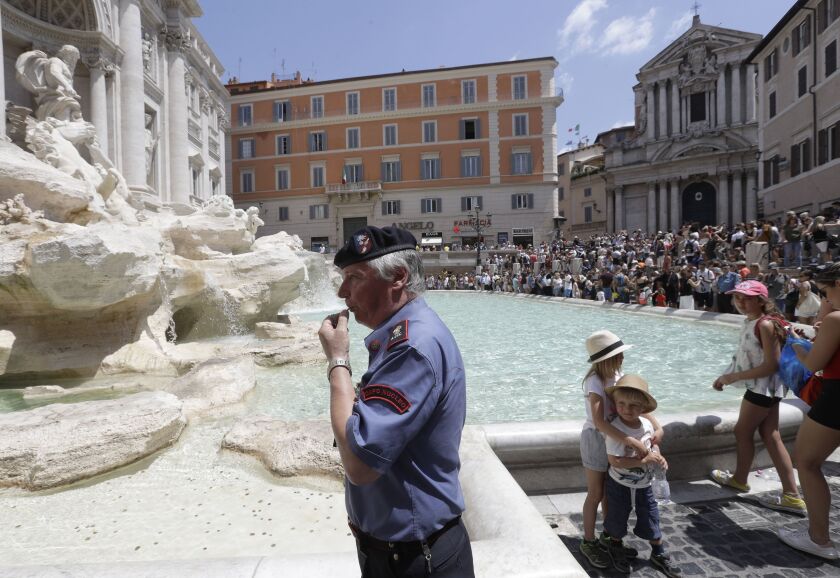 A volunteer blows a whistle in front of renown Trevi Fountain in Rome, Tuesday, July 25, 2017. Visitors are granted access to the border of the fountain in ordinate and controlled flow, under the supervision of two associations of volunteers, after Rome m