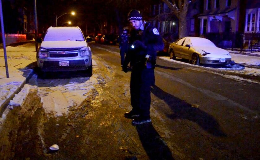 A Chicago Police officer looks for shells casings after two people were shot early this morning on the 6600 block of Evans. | Justin Jackson/ Sun-Times