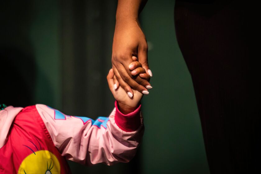 Lizzette, 6, holds hands with councilor Kierra Towns, 25, during Hearts to Art, a summer camp for children whose parents have passed away.