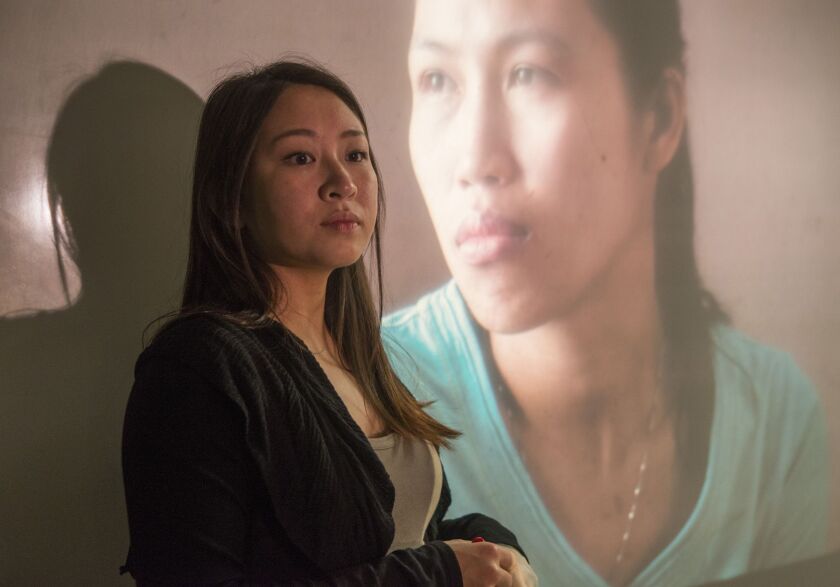 Sarah Lo, with a projected photo from James A. Bowey’s exhibit ‘When Home Won’t Let You Stay,” in Pivot Arts’ world premiere of “Don’t Look Back/Must Look Back.” | MICHAEL BROSILOW