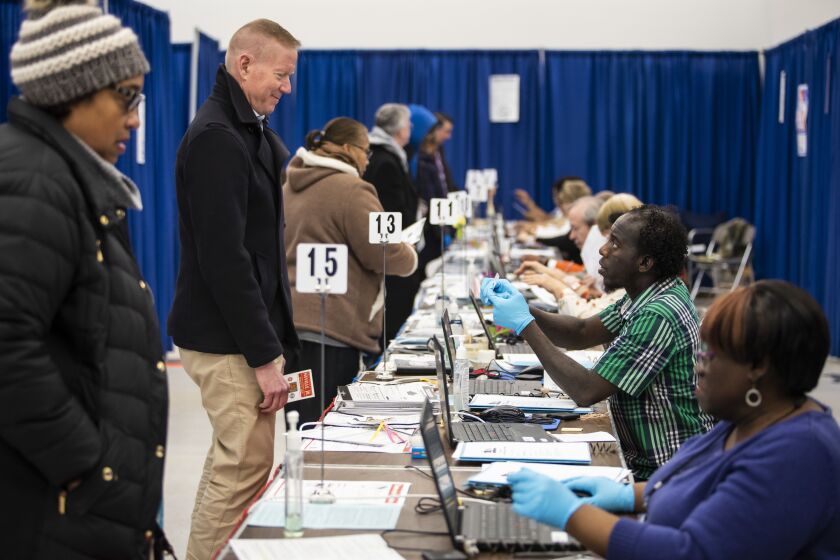 Election officials wear gloves as residents early vote in the March 17 Illinois primary election at the Loop super site at 191 N. Clark St.