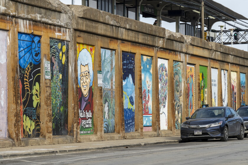 An assortment of murals adorns the side of a Green Line retaining wall in Oak Park.
