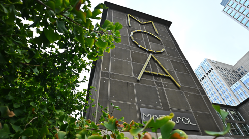 Green foliage frames an exterior view of the Museum of Contemporary Art sign in Chicago on September 9, 2026.