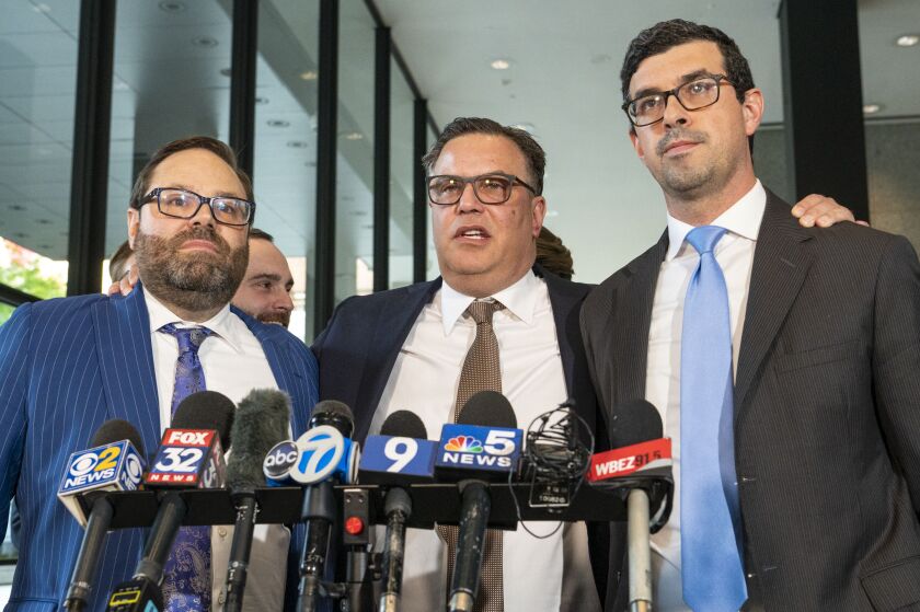 Derrel McDavid, center, grabs the shoulders of his attorneys Beau Brindley, left, and Nadim Glozman.