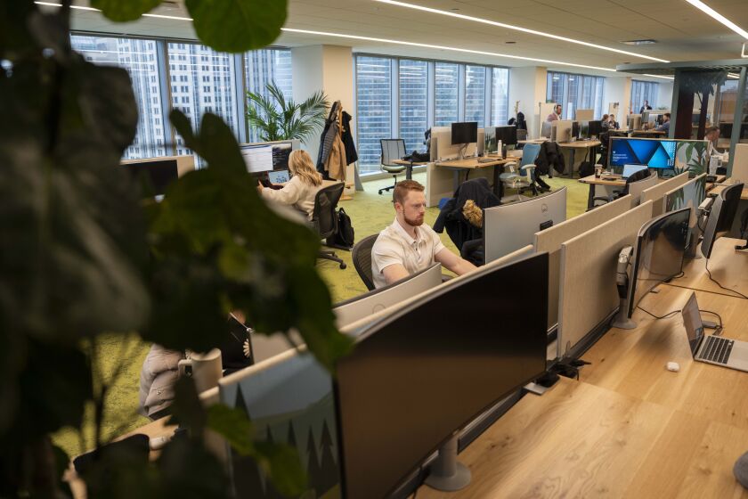 Salesforce employees work at long tables in the company’s new offices at the Salesforce Tower Chicago.