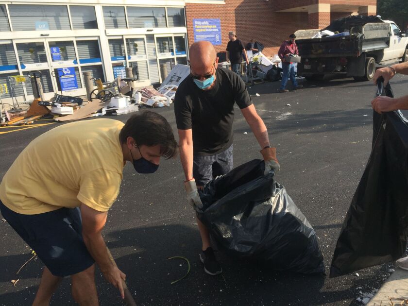 Bruce Alper, 66, of River North, center, helps clean up at a Best Buy near Marcey and Halsted streets.