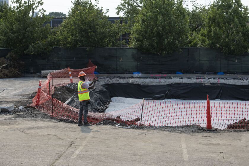 A construction worker takes a photos of the construction site for the Walmart Academy located at the parking lot of the Walmart located at 8331 S. Stewart Ave. in the Chatham neighborhood, Monday, July 19, 2021.