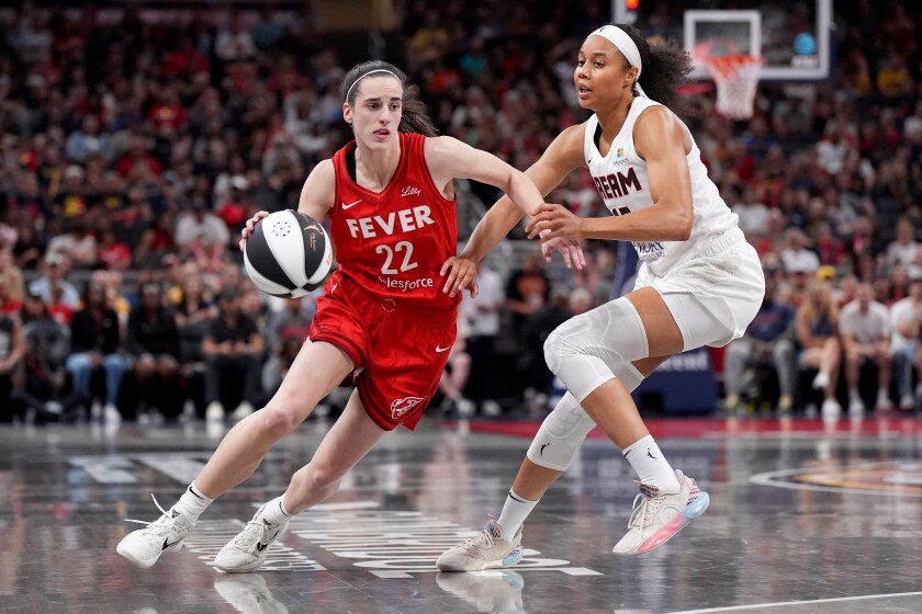 Caitlin Clark (#22) of the Indiana Fever dribbles the ball to the basket against Nia Coffey of the Atlanta Dream.
