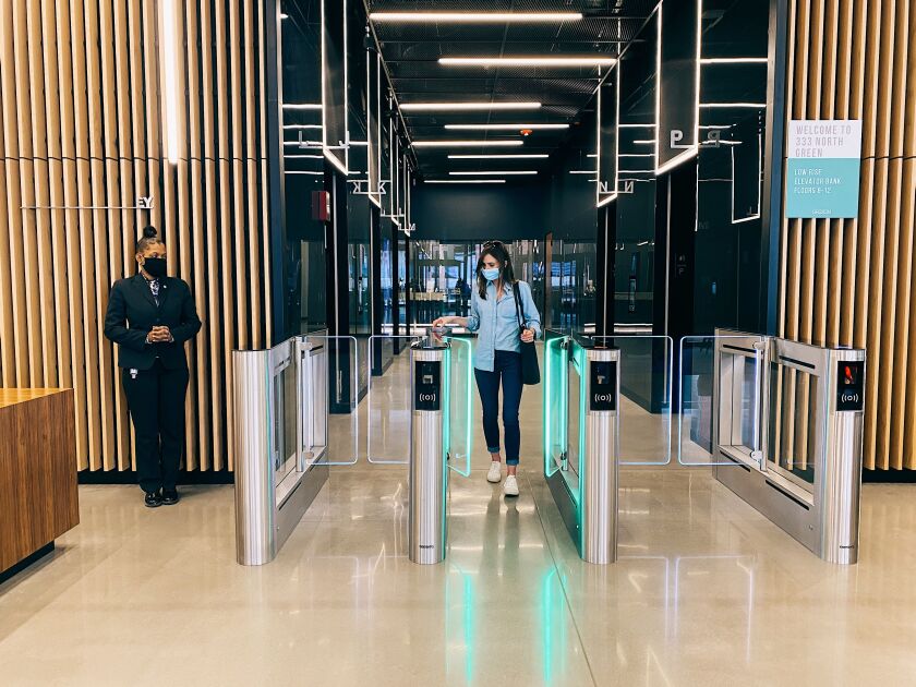 Workers demonstrate a no-touch “destination dispatch” system that Sterling Bay has installed in the office building at 333 N. Green St. in the West Loop.