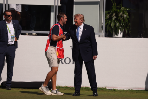 President Donald Trump shakes the hand of a caddie Sunday morning at the Presidents Cup golf tournament in suburban Medinah.