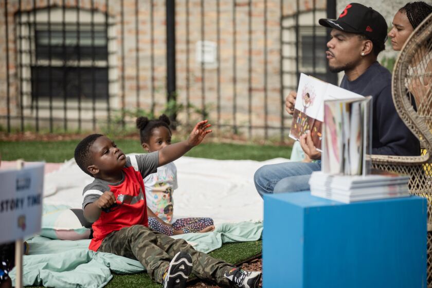 Josiah Wilcher raises his hand while Chance the Rapper reads a book during Chance and Bri’s Books and Breakfast event at Boxville in the Bronzeville neighborhood on Oct. 9.