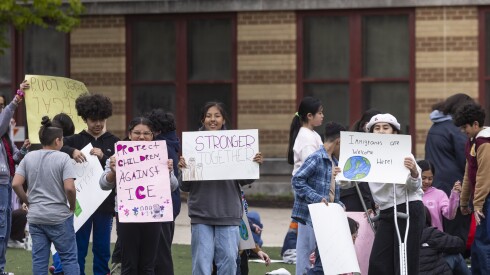 Students hold up homemade signs at a rally at their school.