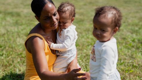 Janita Wiley, mother of twins who said she experienced preeclampsia and was not able to sufficiently breastfeed her children, holds one daughter while reaching out to her other daughter during Latch & Stroll, a resource fair organized by the South Side Birth Center in honor of Black Breastfeeding Week at Russell Square Park in the South Chicago neighborhood on Saturday, Aug. 26, 2023.