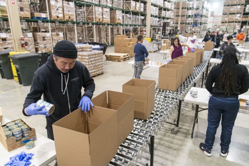 Chef Bill Kim owner of Urban Belly helps break down and repackage food at the Greater Chicago Food Depository.