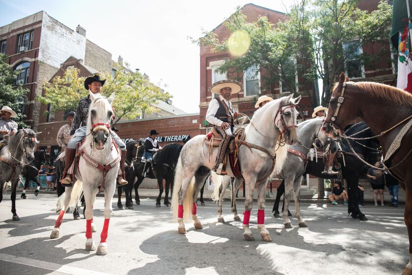 Men riding horses march down West 18th Street in the Pilsen neighborhood during the 20th annual Mexican Independence Day Parade, Saturday afternoon, Sept. 10, 2022.