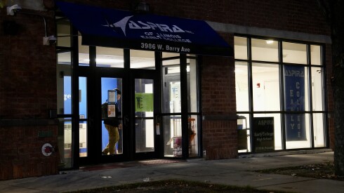 A student wearing khakis exits a school building at night.