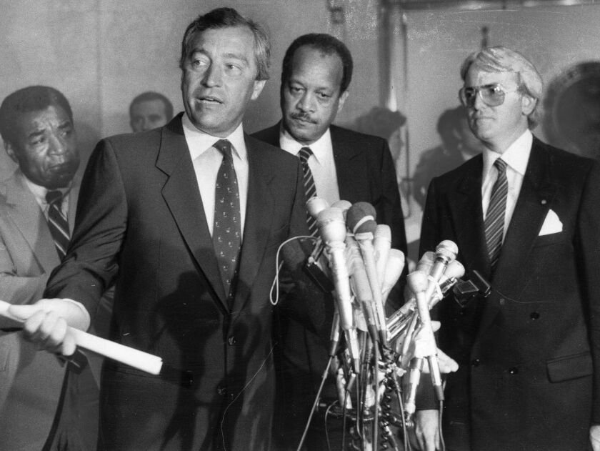 Following the hour-long summit between Mayor Washingrton and leaders of the Vrdolyak 29, Ald Edward R. Vrdolyak (10th) talked to the press in 1984. Watching are (from left) Ald. Wilson Frost (34th), Corporate Counsel James L. Montgomery and Ald. Edward M.